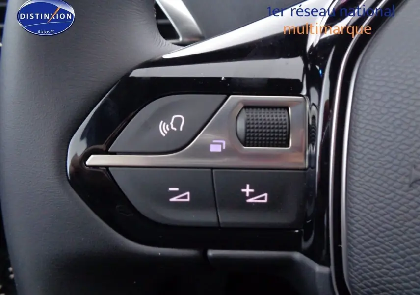 Gros plan sur les commandes de volume et de reconnaissance vocale sur le volant noir brillant d'un Peugeot 3008 2023.