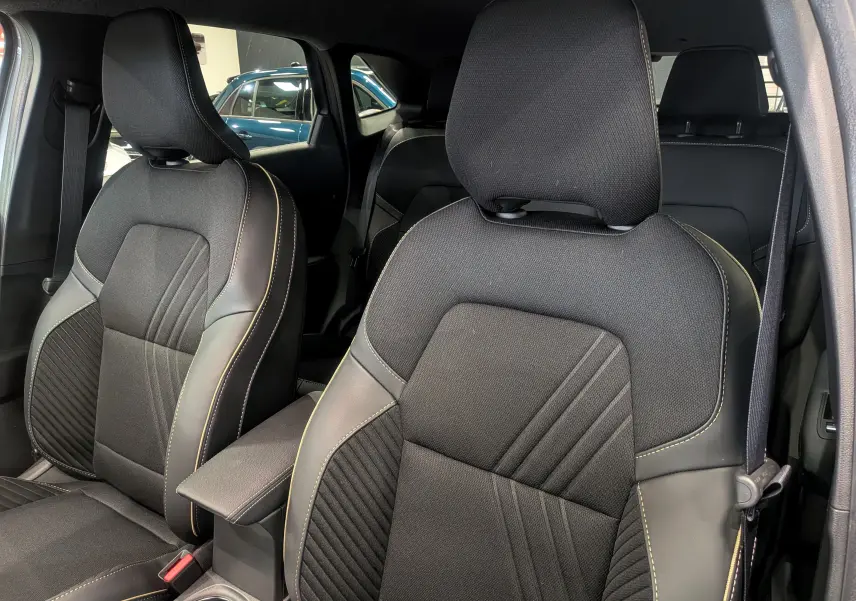 Gros plan sur les sièges avant en tissu noir avec surpiqûres jaunes de la Renault Symbioz gris Cassiopé 2025.