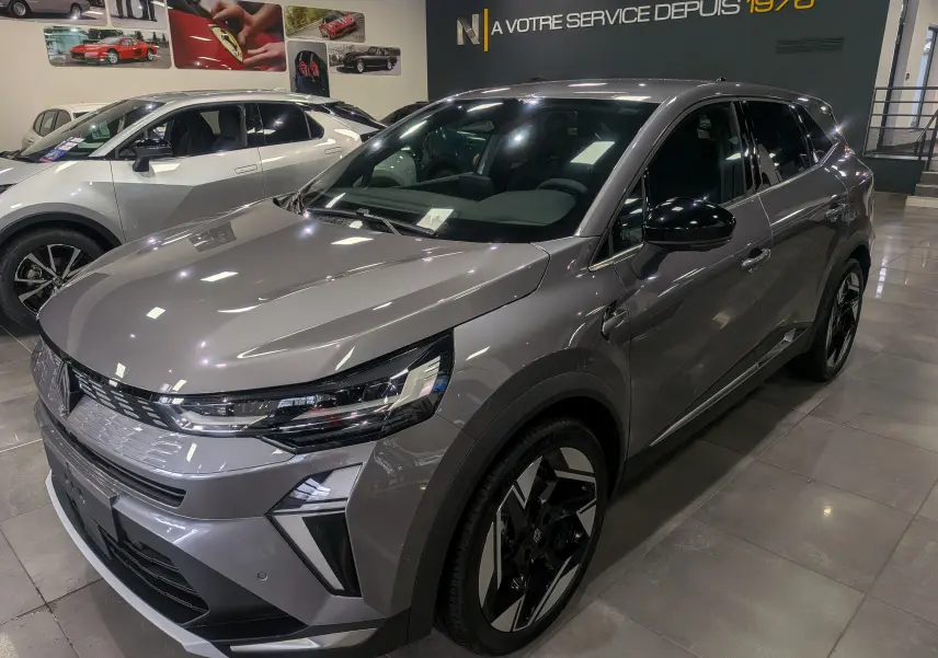 Renault Symbioz E-Tech gris Cassiopé en 3/4 avant droit, avec jantes bicolores et calandre moderne en showroom.