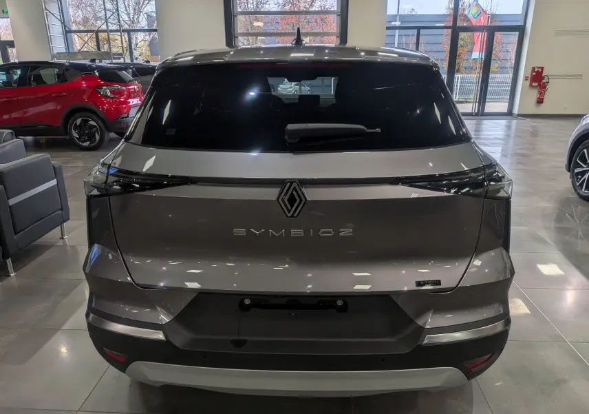 Vue arrière d'un Renault SYMBIOZ gris Cassiopé en showroom, avec logo et feux arrière étirés noirs.