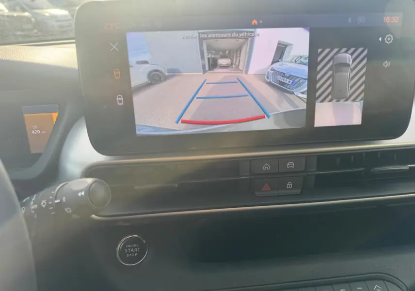 Vue intérieure du tableau de bord du Jeep Avenger gris, écran tactile affichant la caméra de recul et les commandes centrales.