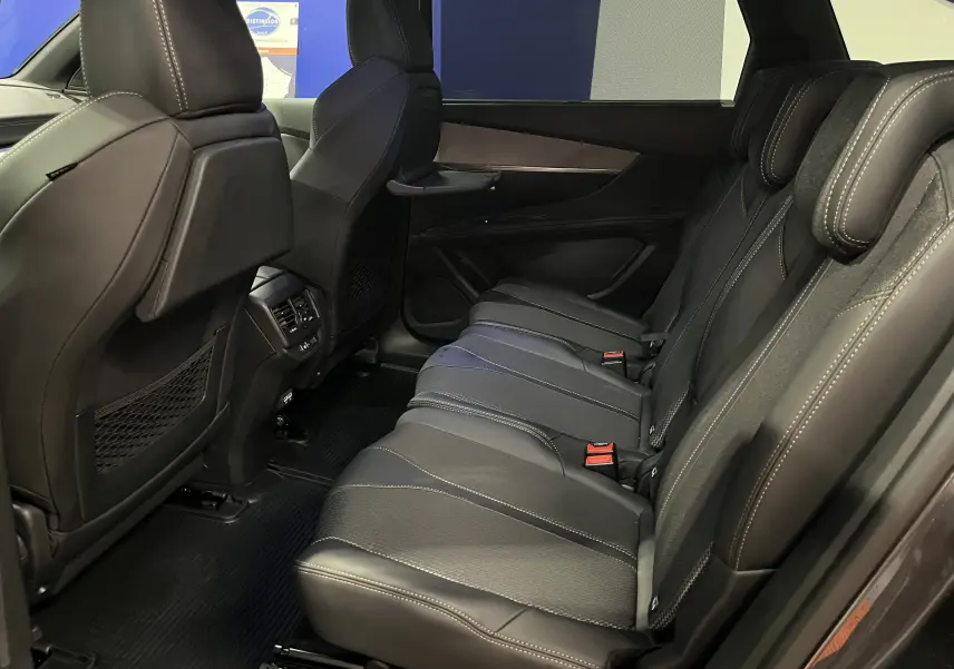 Vue latérale droite de l'intérieur arrière du Peugeot 5008 2024, sièges en cuir noir avec surpiqûres contrastées.