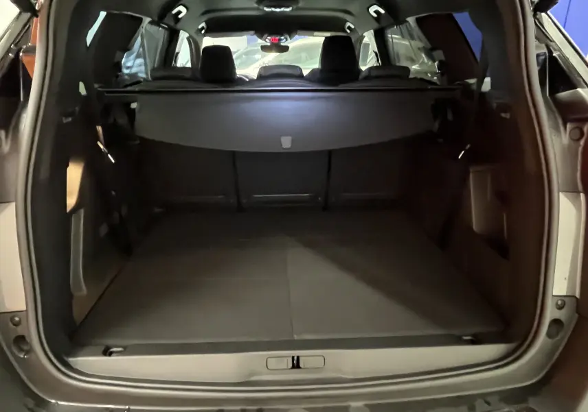 Vue rapprochée du volant noir du Peugeot 5008 2024 GT avec commandes intégrées et logo lion central argenté.