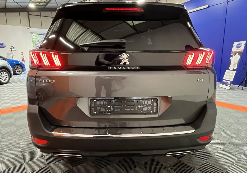 Vue arrière d'un Peugeot 5008 GT gris platinium 2024 avec feux LED allumés dans un showroom.
