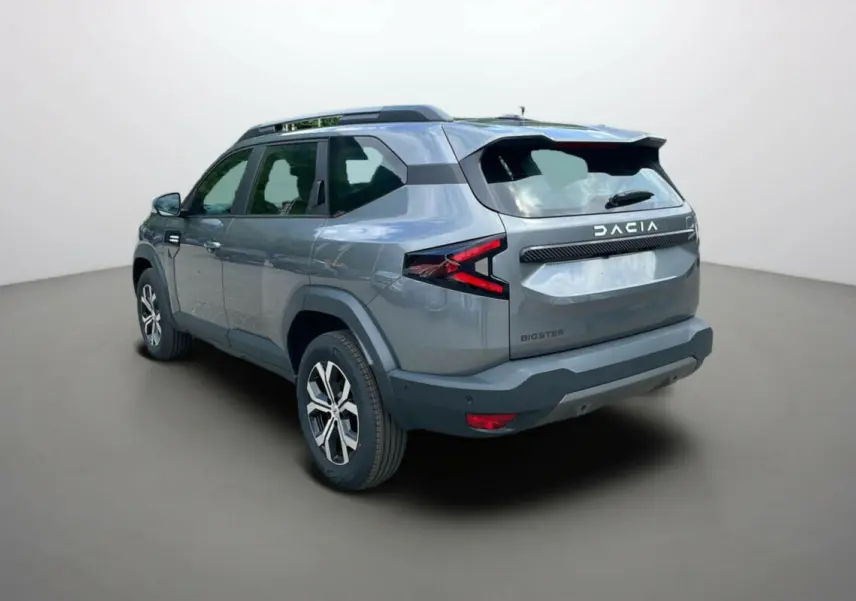 Vue 3/4 arrière droit du SUV Dacia Bigster gris schiste avec barres de toit et jantes alu 17 pouces.