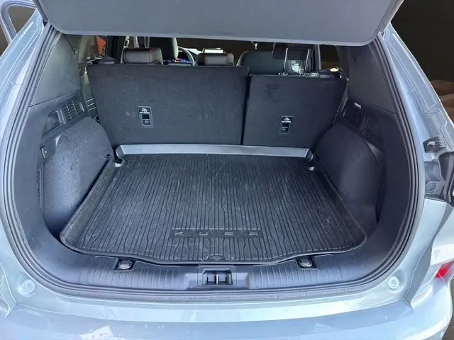 Coffre ouvert vu de l'arrière d'un Ford Kuga gris 2024, version hybride ST-Line X avec tapis de protection noir.