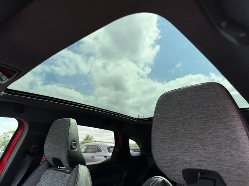 Vue intérieure du Renault Austral Rouge Flamme 2025, mettant en valeur le grand toit panoramique et les sièges gris.