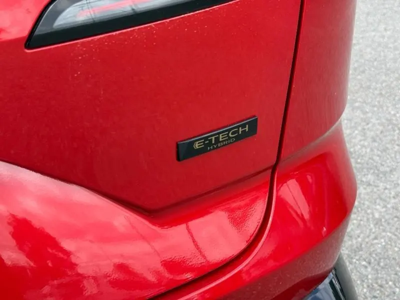 Gros plan sur l'arrière droit rouge Flamme du Renault Austral 2025 avec le badge E-Tech Hybrid visible.