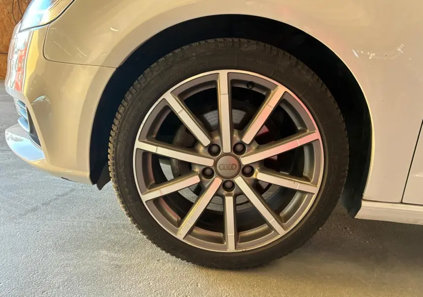 Gros plan sur la roue avant gauche d'une Audi A3 Sportback blanche de 2019 avec jante alliage à dix branches.