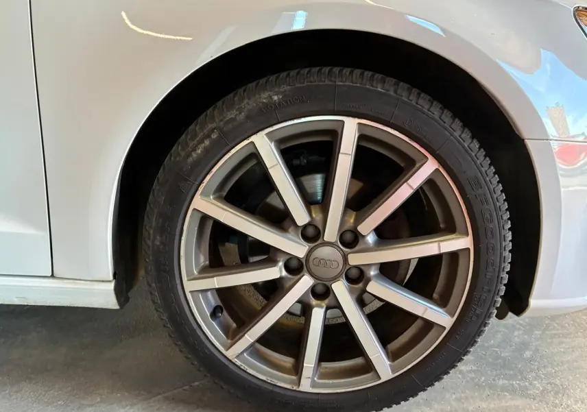 Gros plan sur la roue avant droite d'une Audi A3 Sportback blanche, mettant en valeur la jante alliage à plusieurs branches.