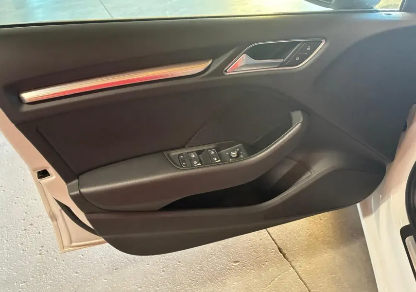 Vue intérieure de la porte avant gauche noire de l'Audi A3 Sportback blanche avec commandes de vitres et verrouillage.