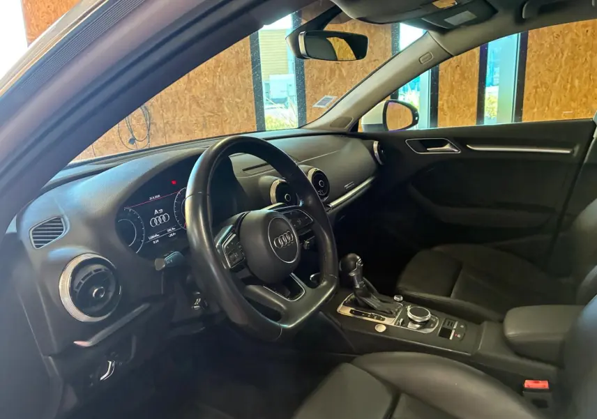 Vue intérieure côté conducteur de l'Audi A3 Sportback 2019 avec tableau de bord et sellerie cuir noire.