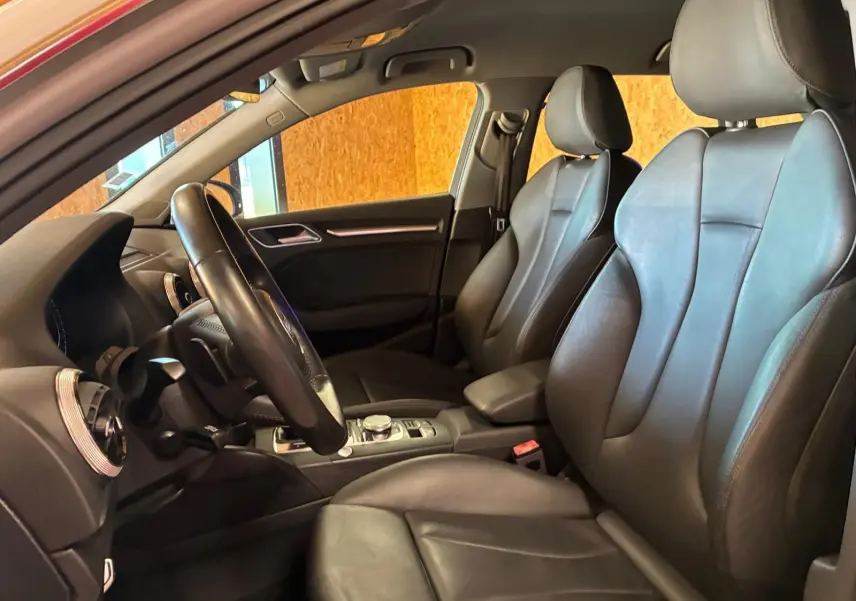 Vue intérieure côté conducteur de l'Audi A3 Sportback 2019 avec sièges cuir noir et tableau de bord moderne.