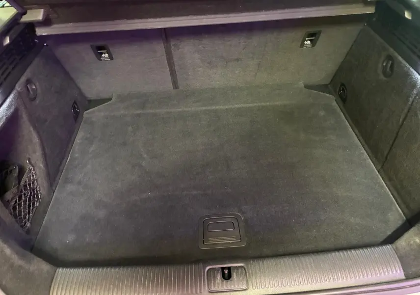 Coffre vide en vue plongeante d'une Audi A3 Sportback blanche, montrant le revêtement intérieur noir et les rangements latéraux.