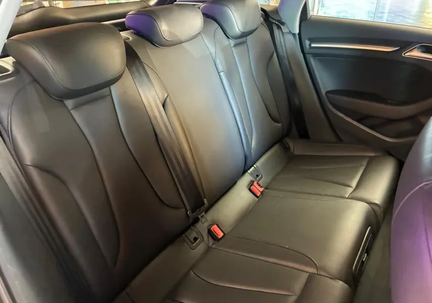 Vue intérieure sur la banquette arrière en cuir noir de l'Audi A3 Sportback, avec ceintures de sécurité visibles.