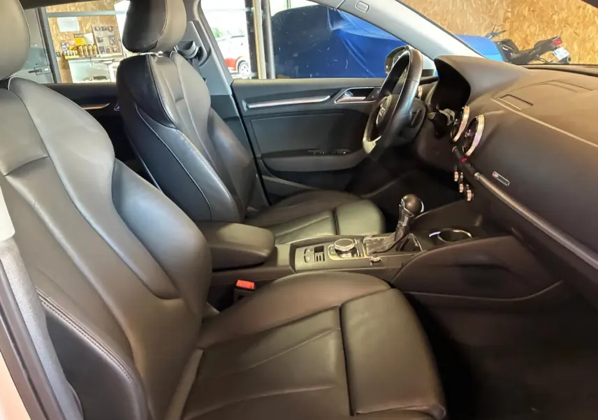 Vue intérieure côté conducteur de l’Audi A3 Sportback 2019 avec sièges cuir noir et tableau de bord moderne.