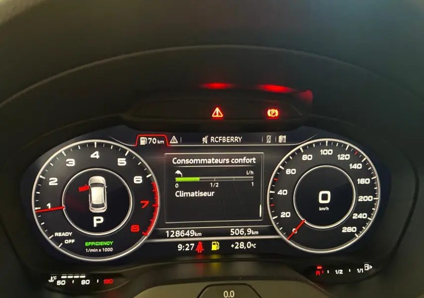 Tableau de bord numérique de l'Audi A3 Sportback blanc, affichant compte-tours, vitesse et consommation, éclairage rouge et blanc.