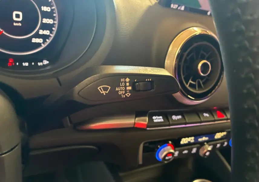 Vue intérieure de l'Audi A3 Sportback 2019, détail du volant, commande d'essuie-glace et aérateur rond chromé.