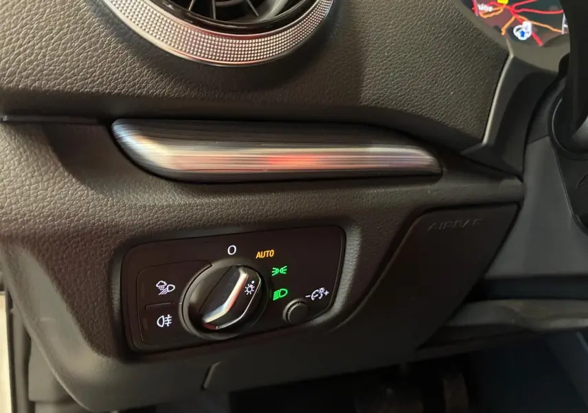 Détail du tableau de bord côté gauche d'une Audi A3 Sportback blanche, avec commande des phares en mode auto et éclairage LED.