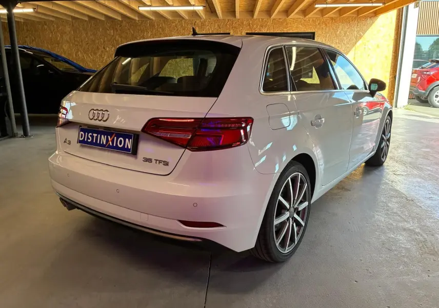 Audi A3 Sportback blanc vue 3/4 arrière droit, avec jantes alliage et feux arrière LED distinctifs.