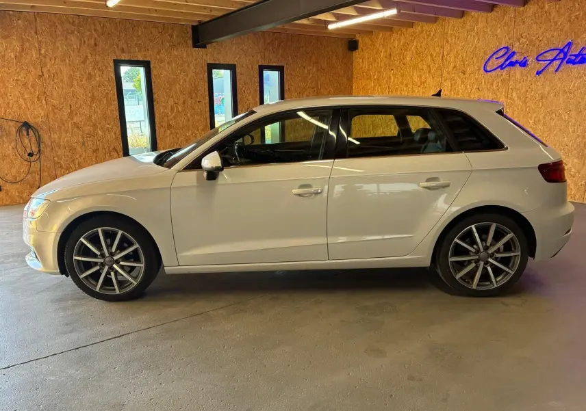 Audi A3 Sportback blanc vue de profil côté gauche, avec jantes alliage et intérieur noir visible à travers les vitres.