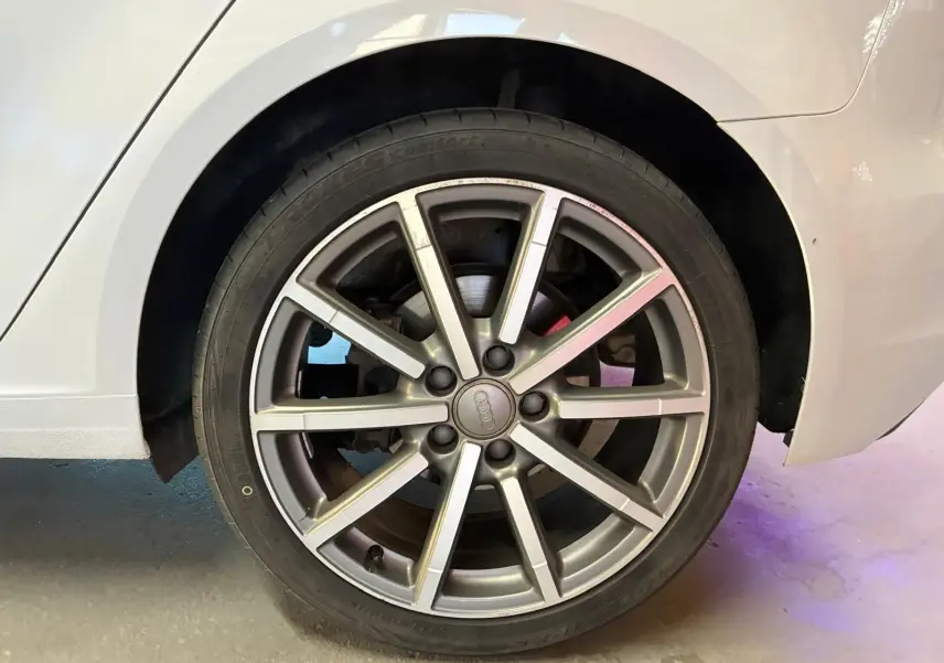 Gros plan sur la roue arrière droite d'une Audi A3 Sportback blanche, mettant en valeur la jante alliage à 10 branches.