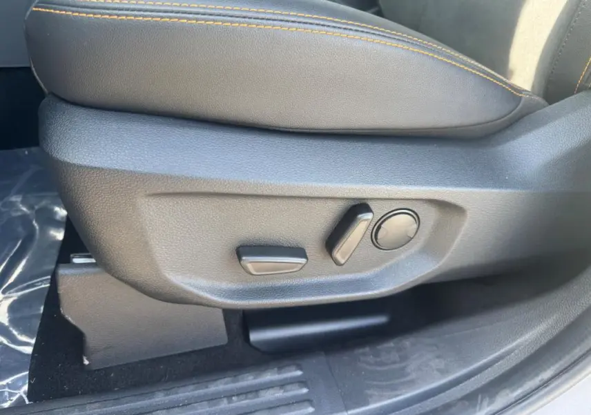 Gros plan sur les commandes de réglage électrique du siège passager en cuir gris avec surpiqûres orange du Ford Ranger 2025.