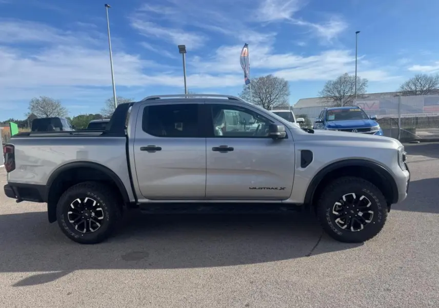 Vue latérale droite d'un Ford Ranger gris 2025 Wildtrak X avec jantes alliage 17 pouces et barres de toit.