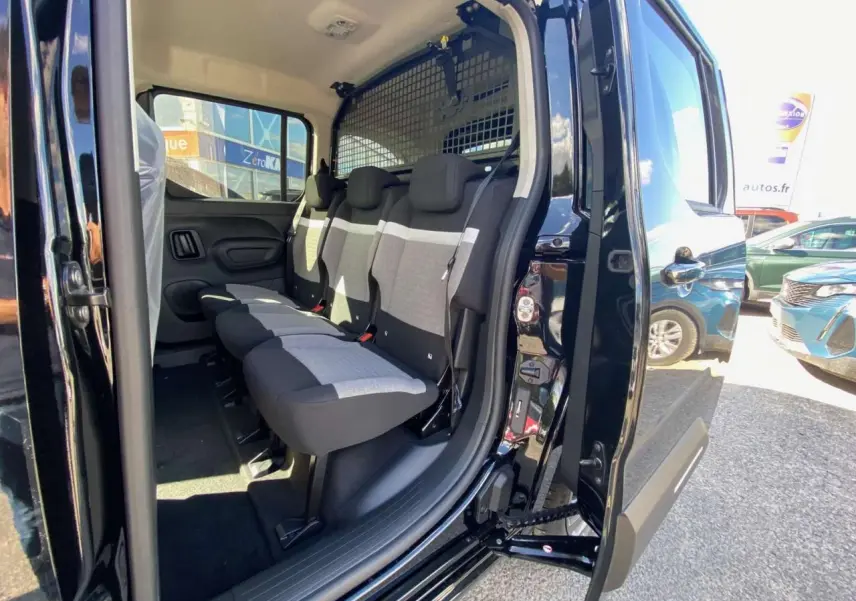 Vue latérale droite du Citroën Berlingo noir 2026 avec porte coulissante ouverte montrant les sièges arrière et la grille de séparation.