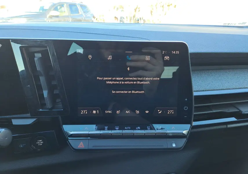 Vue rapprochée de l'écran tactile central du tableau de bord du Renault Austral gris schiste, affichant les commandes climatisation et connectivité Bluetooth.