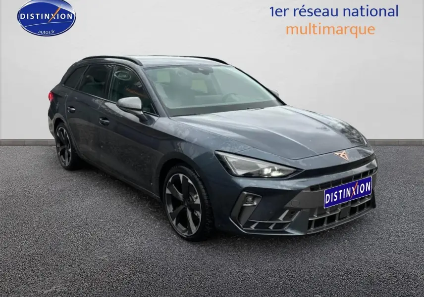 Vue 3/4 avant d'une CUPRA Leon ST 2025 gris magnétique avec jantes alu noires et barres de toit visibles.