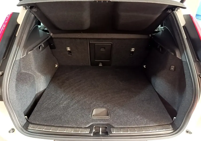 Coffre ouvert vu de l'arrière du Volvo XC40 Recharge T5 262 DCT7 Plus, intérieur noir et moquette épaisse.