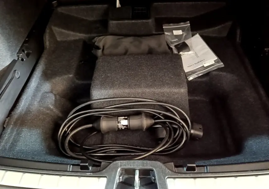 Vue plongeante sur le coffre noir d'un Volvo XC40 Recharge T5 262 avec câble de charge et accessoires rangés.