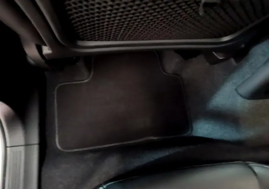 Vue rapprochée du tapis de sol noir côté passager avant du Volvo XC40 Recharge T5 2023, intérieur sombre.