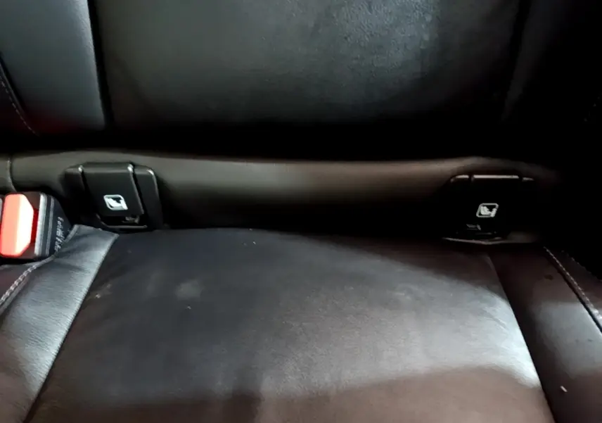 Gros plan sur la banquette arrière noire en cuir du Volvo XC40 Recharge T5, montrant les fixations Isofix et la ceinture de sécurité.