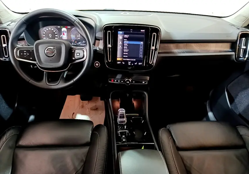 Vue intérieure avant du Volvo XC40 Recharge T5 262 DCT7 Plus 2023, tableau de bord noir avec écran tactile central et volant cuir.