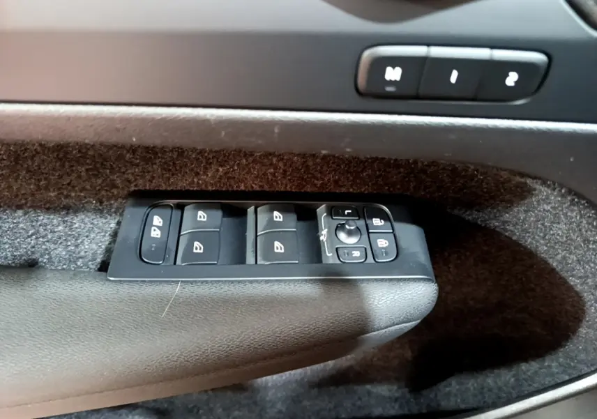 Gros plan sur les commandes de lève-vitres et réglages des rétroviseurs côté gauche intérieur d’un Volvo XC40 2023 hybride rechargeable.