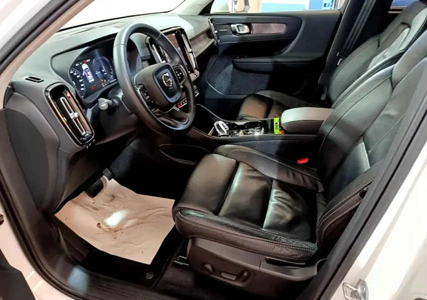 Vue intérieure côté conducteur du Volvo XC40 Recharge T5 262 DCT7 Plus 2023, sièges cuir noir et tableau de bord moderne.