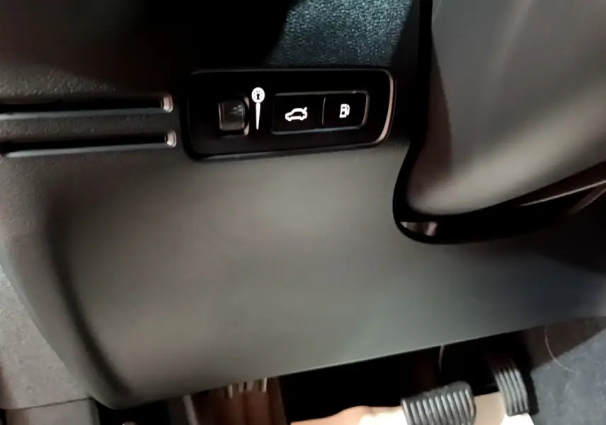 Détail intérieur montrant les commandes d’ouverture du coffre et du réservoir sur un Volvo XC40 hybride rechargeable 2023.