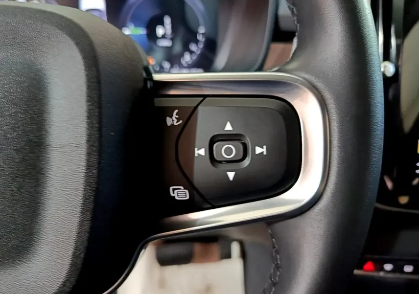 Gros plan sur les commandes noires et argentées du volant cuir noir du Volvo XC40 Recharge T5 2023.