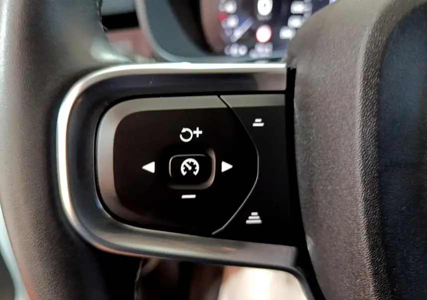 Gros plan sur les commandes du régulateur de vitesse au volant noir et argent du Volvo XC40 hybride rechargeable.