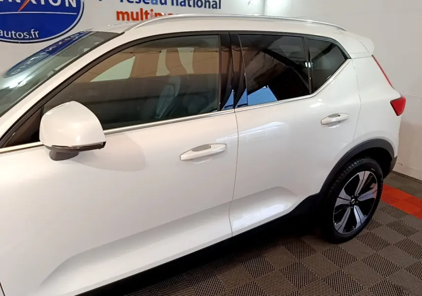 Vue latérale droite d'un Volvo XC40 hybride rechargeable blanc avec jantes noires et détails chromés.
