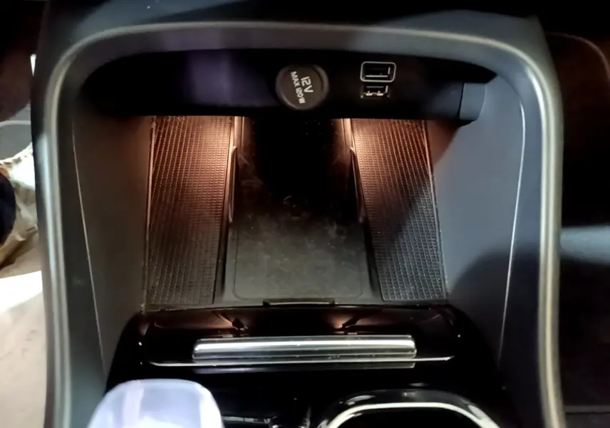 Vue plongeante sur la console centrale noire du Volvo XC40 Recharge T5 avec prise 12V et port USB visibles.