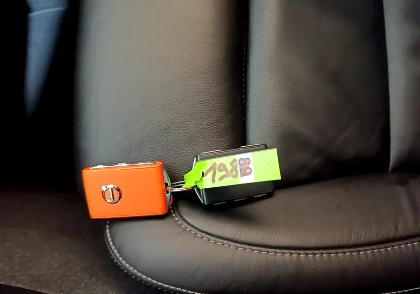 Clé orange Volvo posée sur siège en cuir noir à couture apparente, vue rapprochée intérieure du véhicule.