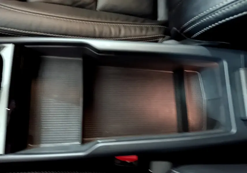 Vue rapprochée de la console centrale noire avec rangement ouvert et sellerie cuir sombre du Volvo XC40 Recharge T5 2023.