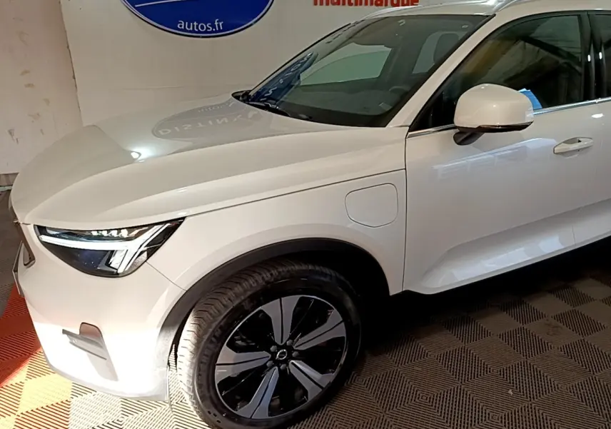 Vue 3/4 avant droit d'un Volvo XC40 hybride rechargeable blanc avec jantes noires et détails modernes.