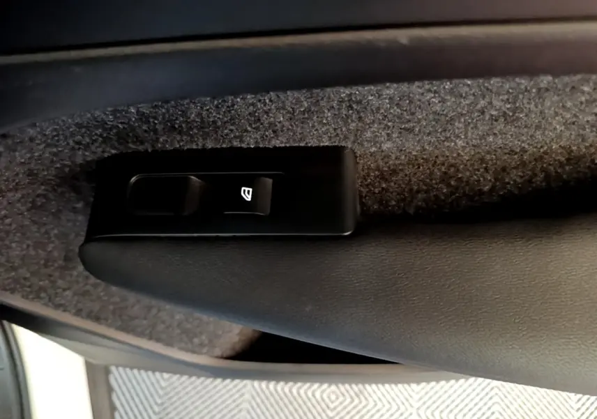 Détail du bouton de commande de vitre électrique sur la porte intérieure noire d’un Volvo XC40 hybride rechargeable.