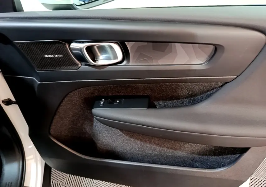 Vue rapprochée de la porte avant gauche du Volvo XC40 hybride rechargeable, avec insert décoratif et commande de vitre noire.