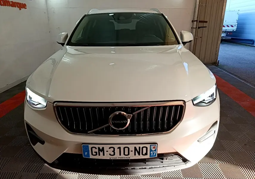 Vue frontale d'un Volvo XC40 Recharge T5 blanc avec calandre noire et phares LED allumés en intérieur.