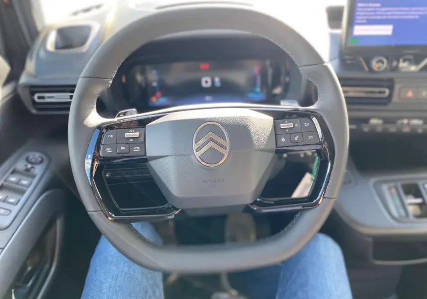 Vue intérieure centrée sur le volant multifonction noir du Citroën Berlingo avec tableau de bord et écran tactile en arrière-plan.
